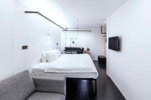 een slaapkamer met een bed en een bank bij Hotel Mono in Singapore