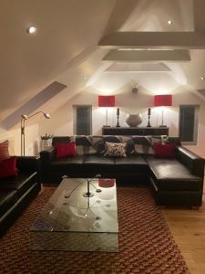 ein Wohnzimmer mit einem schwarzen Sofa und einem Tisch in der Unterkunft Invercreran Lodge Luxury Bed & Breakfast in Appin
