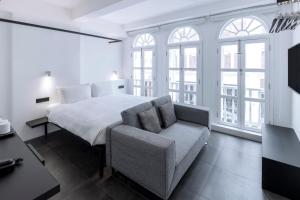 een slaapkamer met een bed, een stoel en ramen bij Hotel Mono in Singapore
