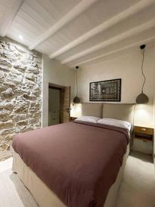 a bedroom with a large bed and a stone wall at Nespola di Campiello in Corfu