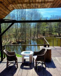 eine Terrasse mit 2 Stühlen, einem Tisch und einem See in der Unterkunft Dom Rybaka in Mirosławiec