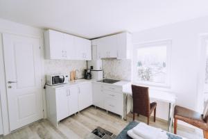 a white kitchen with white cabinets and a microwave at Casa Dany in Bistriţa