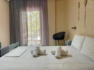 a bedroom with a white bed with two pillows on it at Hotel Argilos in Asprovalta