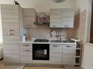 eine Küche mit Holzschränken, einem Herd und einer Spüle in der Unterkunft Il nido di Angelina - Ascea in Ascea