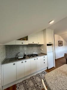 eine Küche mit weißen Schränken, einer Spüle und einem Kühlschrank in der Unterkunft Casa en San Pantaleón in Paderne