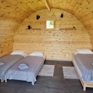 two beds in a room with a wooden wall at Camp Genys in Jurbarkas