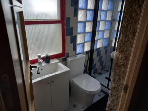 baño con aseo y lavabo y ventana en A CASA de FLORINDA, en Oia