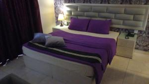 um quarto com uma cama grande e almofadas roxas em Beirut Hotel em Amã