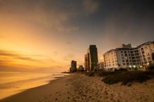 ein Strand mit Gebäuden und das Meer bei Sonnenuntergang in der Unterkunft Ocean Breeze Hotel in Strand