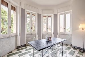 comedor con mesa, sillas y ventanas en AwesHomeItaly - Bay Windows Apartment, en La Spezia