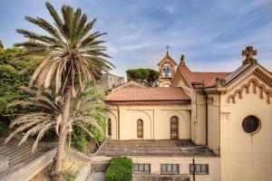 a church with a palm tree in front of it at AwesHomeItaly - Bay Windows Apartment in La Spezia