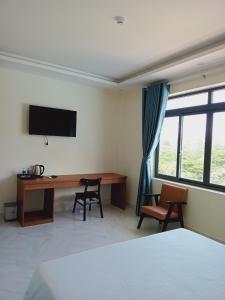 1 dormitorio con escritorio, TV y sillas en Hoàng Anh Côn Đảo Hotel en Con Dao
