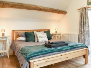 a bedroom with a bed with a green blanket at The Barn in Llangwm