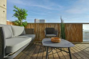 a couch on a deck with a table and a chair at Modern 3-BR near Beach Club by HolyGuest in Tel Aviv