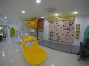 un toboggan jaune dans une pièce avec un mur d'escalade dans l'établissement CoCo Fun House Kemaman with Pool and Bathtub, à Kampong Gong Pauh