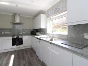 a kitchen with white cabinets and a sink and a window at Borve House, Kilchoan in Kilchoan