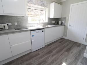 a kitchen with white cabinets and a wooden floor at Borve House, Kilchoan in Kilchoan