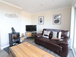 a living room with a leather couch and a tv at Borve House, Kilchoan in Kilchoan