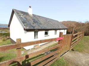 a white house behind a wooden fence at Borve House, Kilchoan in Kilchoan