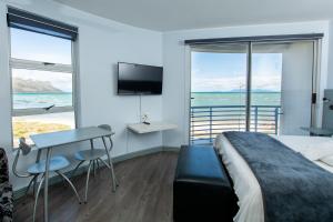 a bedroom with a bed and a table and a television at Ocean Breeze Hotel in Strand