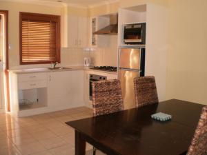 a kitchen with a table and a refrigerator at Best Western Colonial Village Motel in Warrnambool
