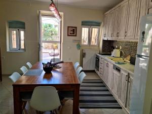 a kitchen with a wooden table and white chairs at Villa Maxim in Corfu Town in Corfu