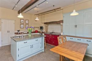a kitchen with white cabinets and a wooden table at Large Country Farmhouse in Waddington