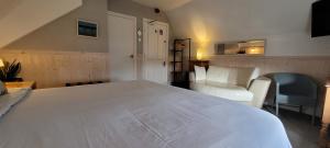um quarto com uma grande cama branca e uma cadeira em The Mon Fort em Bridlington