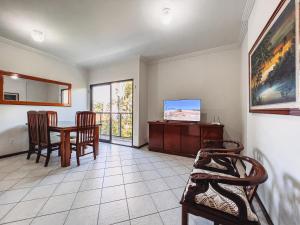 a living room with a table and chairs and a tv at Dois quartos com ar a 190 m de praia Paradisíaca in Guarapari +30 photos