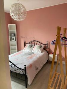 um quarto com uma cama com paredes cor-de-rosa e um lustre em Maison de ville em Bort-les-Orgues