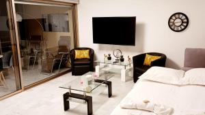 ein Wohnzimmer mit einem Sofa, Stühlen und einem TV in der Unterkunft Licorne G14 in Cannes