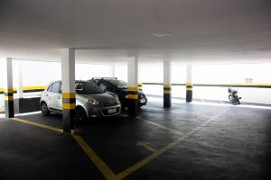 a parking garage with two cars and a motorcycle at Hotel Ellegance in Salvador