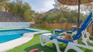 um quintal com uma piscina e duas cadeiras e um guarda-sol em Casa Rural Las Angosturas (Caminito del Rey) em El Chorro