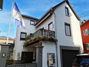 ein weißes Gebäude mit einem Balkon und einer Flagge in der Unterkunft Haus Grewe in Kaub in Kaub