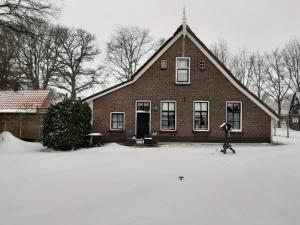 une personne marchant dans la neige devant une maison dans l'établissement Vakantiewoning 't Veurhuus, à Bergentheim
