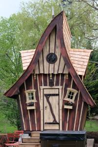 uma casa de brincar com um telhado alto e uma porta em La cabane de Merlin em Les Molières
