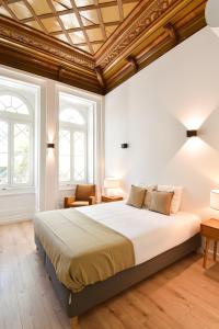 a bedroom with a large bed and two windows at LAA Studios in Coimbra