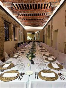 uma mesa longa com toalhas de mesa brancas e copos de vinho em Casa del Armiño Mansión de la Familia de "El Greco" em Toledo