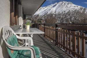 a table and chairs on a balcony with a snow covered mountain at Apartments Bergrose in Saas-Fee