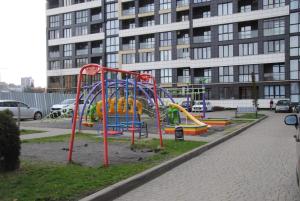 een speeltuin met een glijbaan in een park met een gebouw bij Apartment Porohova in Lviv