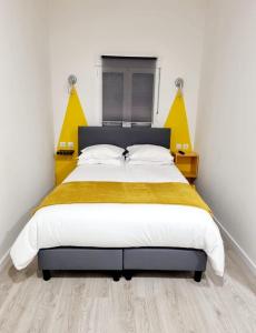 1 dormitorio con 1 cama grande decorada en tonos amarillos en Azulrelax Hostel, en Pinhal Novo