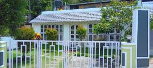 uma cerca branca em frente a uma pequena casa em Serene Blossom Valley em Tenkasi