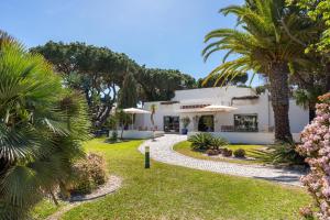 ein weißes Haus mit Palmen und einem Garten in der Unterkunft Balaia Golf Poolside Retreat - Superior 2 bed villa in Albufeira