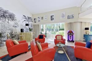 uma sala de estar com cadeiras vermelhas e uma mesa em Les Jardins de la Muse, piscine couverte, spa et fitness em Basse-Goulaine