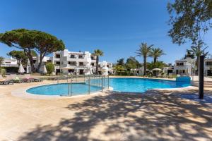 einen Pool in einem Resort mit Palmen und Gebäuden in der Unterkunft Balaia Golf Poolside Retreat - Superior 2 bed villa in Albufeira