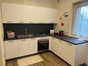 una cucina con armadi bianchi e piano di lavoro nero di Appartamento Monte a Ponte Caffaro