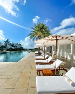 a row of lounge chairs with umbrellas next to a pool at Aurora Anguilla Resort & Golf Club in Ebenezer