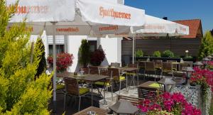 a patio with tables and chairs and an umbrella at Gasthof Alte Schule in Fürstenzell