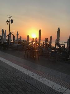 ein Sonnenuntergang mit Tischen, Stühlen und Sonnenschirmen in der Unterkunft Jozy in Peraia
