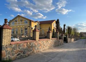 a house with a stone wall and a fence at Готель МАГНАТ 